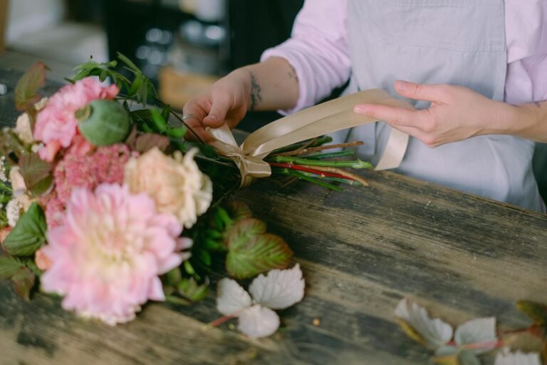 Florist arranging a beautiful floral bouquet with delicate hands and soft petals indoors.