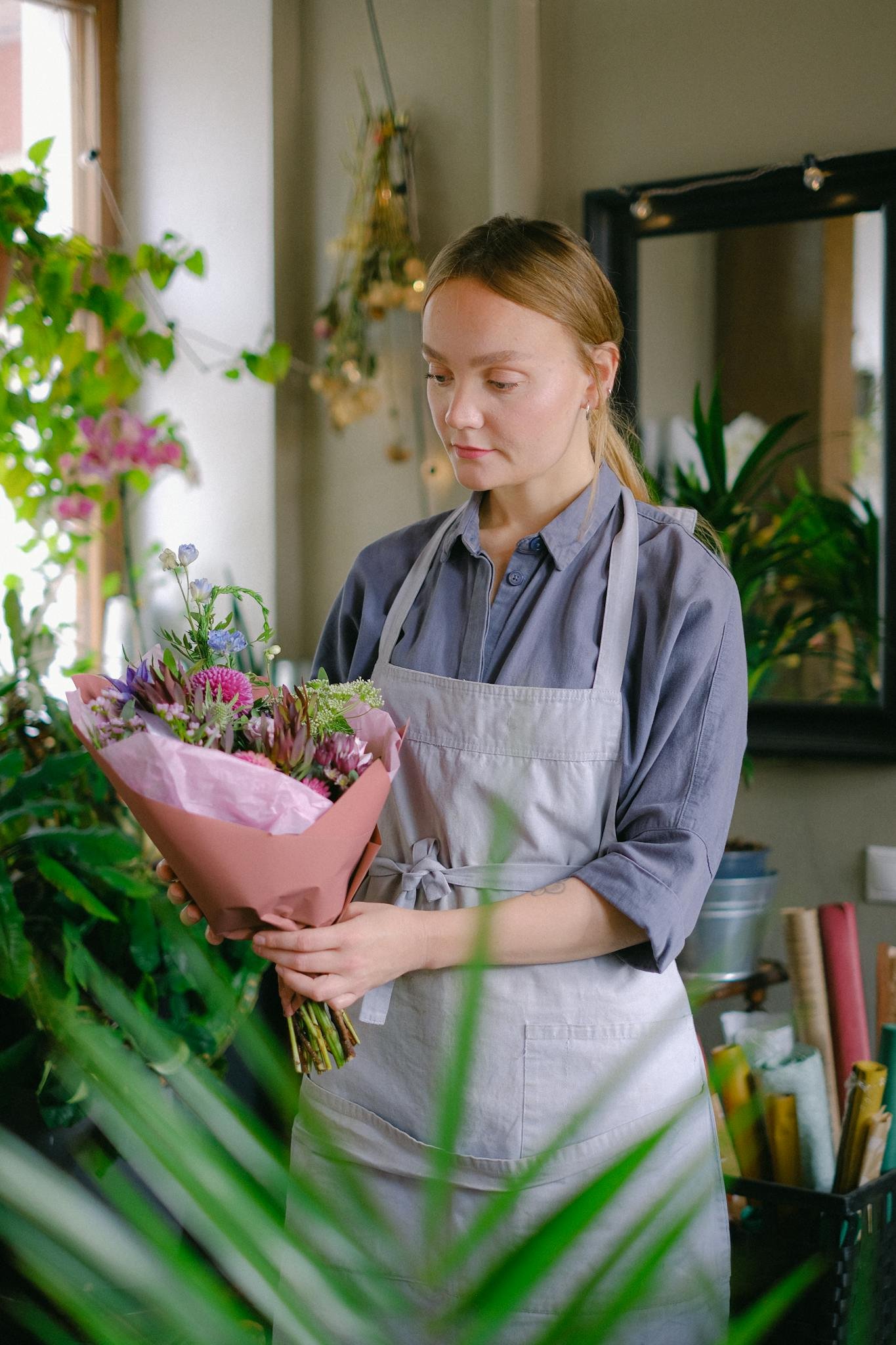 Florist in apron arranging a vibrant bouquet in a cozy flower shop.